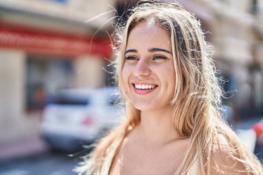 Young blonde woman smiling confident looking to the side at street