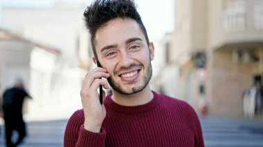 Genç İspanyol adam gülümsüyor. Kendine güveniyor. Sokakta akıllı telefondan konuşuyor.