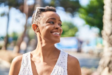 Afro-Amerikalı kadın gülümsüyor. Kendinden emin bir şekilde caddeye bakıyor.