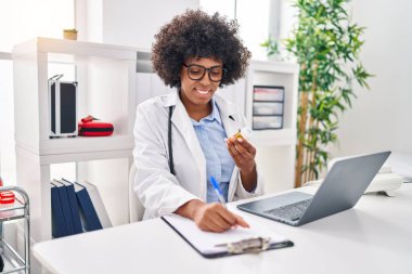 Afrikalı Amerikalı kadın doktor klinikte doküman reçetesi yazıyor.