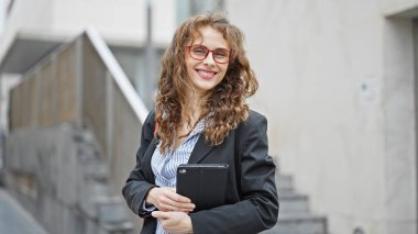 Sokakta gülümseyen dokunmatik ped kullanan genç bir iş kadını.