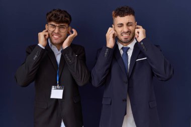 İki İspanyol iş adamı yüksek sesli müzik sesi için kulaklarını parmaklarıyla kapatıyor. sağır kavramı. 