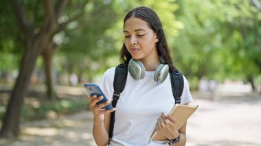 Parkta akıllı telefon rehberi kullanan Afrikalı Amerikalı bir kız öğrenci.