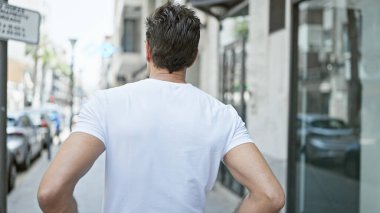 Genç İspanyol adam caddede geri geri duruyor.