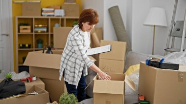 Orta yaşlı bir kadın gülümsüyor. Kendine güveni tam, yeni evini kontrol ediyor.