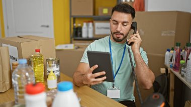 Genç Arap gönüllü dokunmatik ped kullanarak yardım merkezinde telefonla konuşuyor.