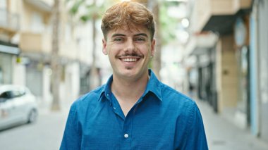 Sokakta kendinden emin gülümseyen İspanyol genç adam.