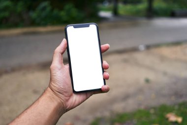 Elinde akıllı telefon tutan adam sokakta beyaz beyaz ekran gösteriyor