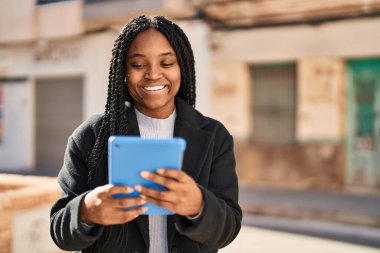 African american woman smiling confident using touchpad at street