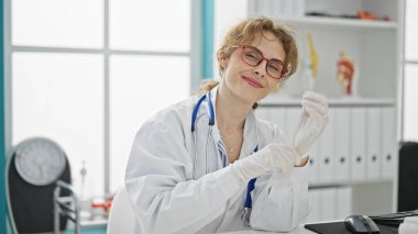 Klinikte gülümseyen eldivenli genç bayan doktor.
