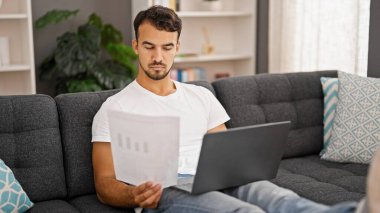 Genç İspanyol adam evde bilgisayar kağıdı kullanıyor.