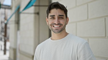 Sokakta kendinden emin gülümseyen İspanyol genç adam.