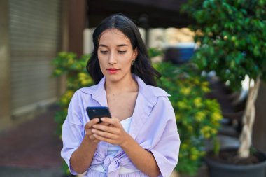 Genç ve güzel İspanyol kadın akıllı telefon kullanıyor. Sokakta ciddi bir ifadesi var.