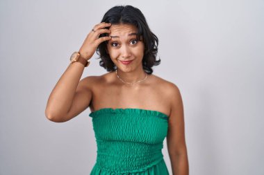 Young hispanic woman standing over isolated background worried and stressed about a problem with hand on forehead, nervous and anxious for crisis 