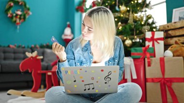 Laptop ve kredi kartıyla alışveriş yapan genç ve güzel İspanyol kadın Noel 'i evde kutluyor.