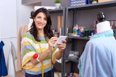 Orta yaşlı İspanyol kadın terzi atölyedeki deftere kendinden emin bir şekilde yazıyor.