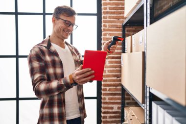 Young man ecommerce business worker scanning package using touchpad at office