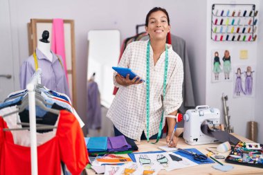 Terzi dükkanında deftere dokunmatik defter yazan genç ve güzel İspanyol bir kadın.