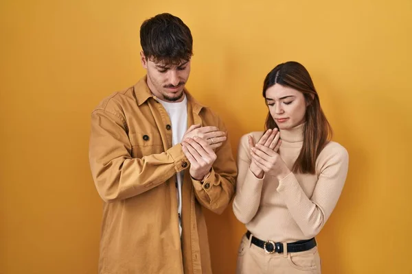 Young Hispanic Couple Standing Yellow Background Suffering Pain Hands Fingers — Stock Photo, Image