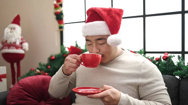 Νεαρός Κινέζος Που Πίνει Καφέ Καθισμένος Στον Καναπέ Χριστουγεννιάτικη Διακόσμηση — Φωτογραφία Αρχείου