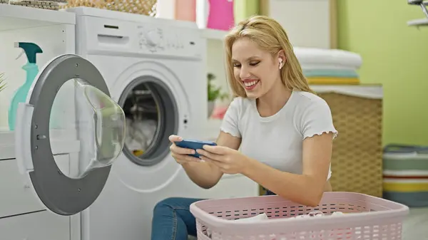 洗濯室でビデオゲームをプレイしている若い金髪の女性 — ストック写真