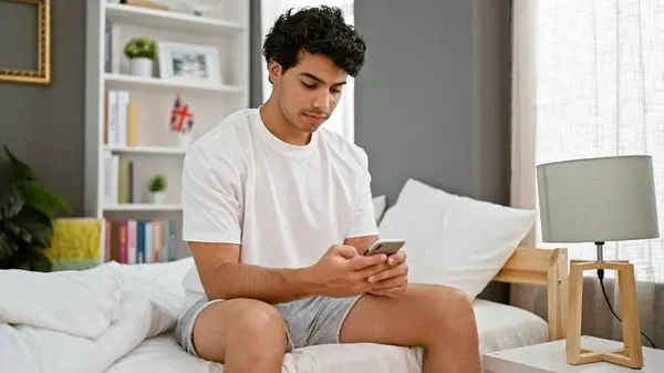 Jonge Latijnse Man Met Behulp Van Smartphone Zitten Bed Slaapkamer — Stockfoto