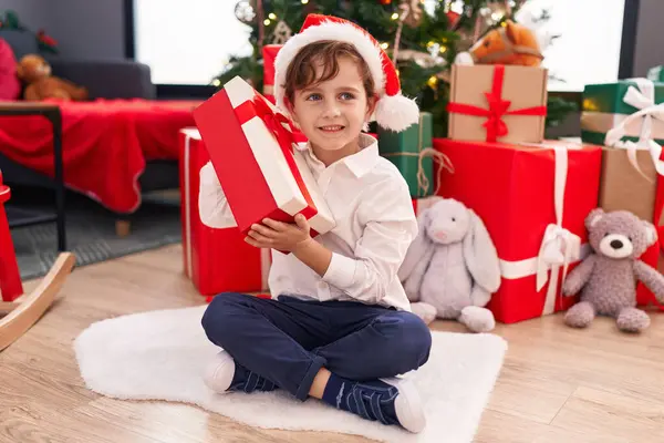 Entzückender Hispanischer Junge Hört Geschenkgeräusche Wenn Hause Weihnachtsbaum Sitzt — Stockfoto
