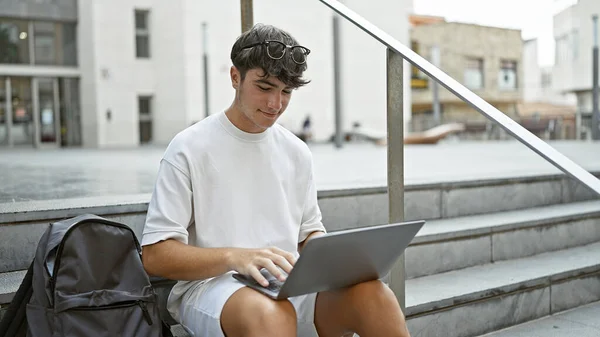 クールな若いヒスパニック系ティーンエイジャーは自信を放射し 大学生活をナビゲートし 大学の階段に座り ノートパソコンで技術に没頭した — ストック写真