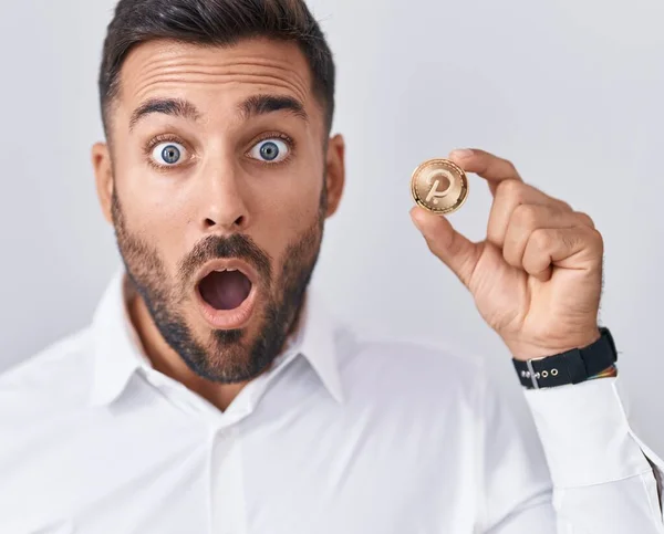 Handsome Hispanic Man Holding Polkadot Cryptocurrency Coin Scared Amazed Open — Stock Photo, Image