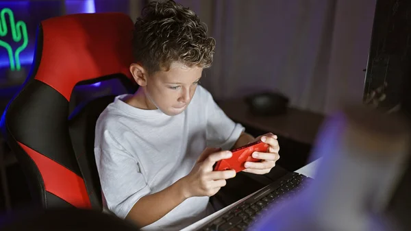 可爱的金发男孩流口水了 沉迷于严肃的游戏中 从一个舒适的游戏室里直播他的智能手机游戏 — 图库照片