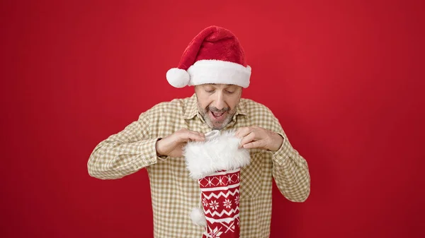 Middle Age Man Wearing Christmas Hat Looking Sock Isolated Red — Stock Photo, Image