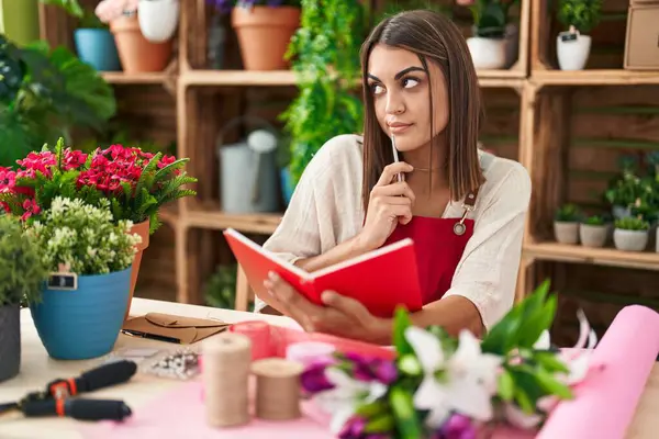 Young Beautiful Hispanic Woman Florist Reading Notebook Doubt Expression Flower —  Fotos de Stock