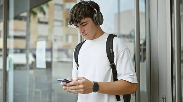 音楽に没頭したクールな若いヒスパニック大学の学生 キャンパスの日光の下でスマートフォン画面をタップ — ストック写真