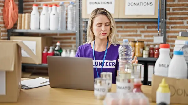 Genç Sarışın Kadın Gönüllü Olarak Yardım Merkezinde Laptopunu Kullanarak Yiyecekleri — Stok fotoğraf