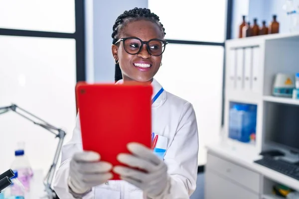 African american woman scientist smiling confident using laptop at laboratory