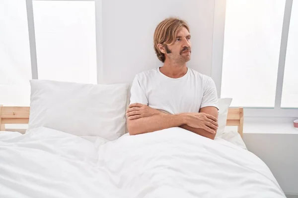 Young Blond Man Sitting Bed Serious Expression Arms Crossed Gesture — Stock Photo, Image