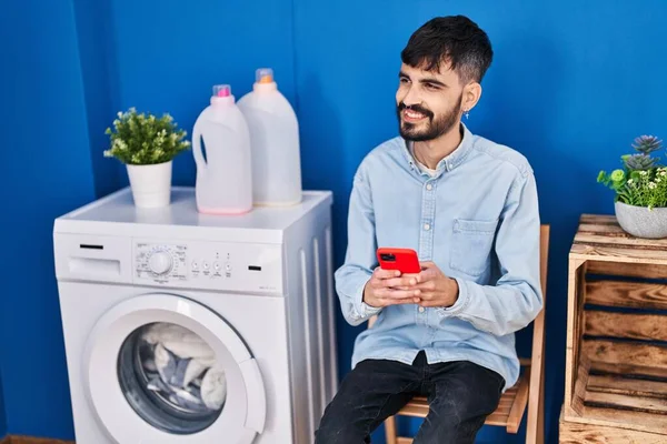 Jonge Spaanse Man Met Smartphone Wachtend Een Wasmachine Wasruimte — Stockfoto