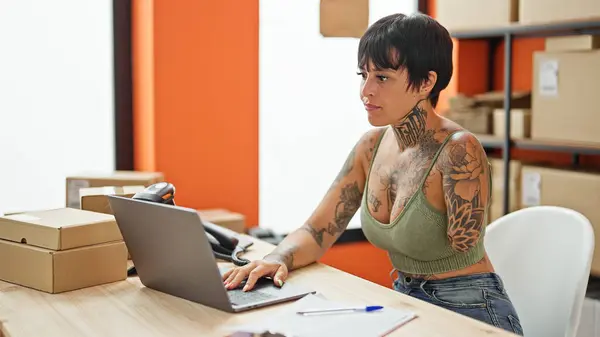 西班牙妇女与截肢者电子商务工人使用笔记本电脑与严重的脸在办公室 — 图库照片