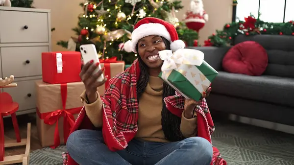 African woman taking selfie picture with christmas present at home