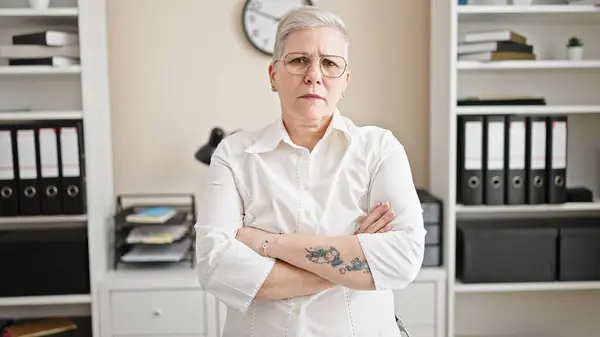 オフィスで腕を組んで立っている中年の白髪の女性のビジネスワーカー — ストック写真