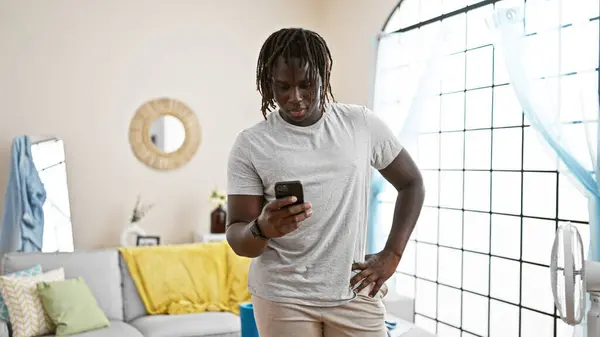 Africký Američan Stojí Vážnou Tváří Pomocí Smartphone Doma — Stock fotografie