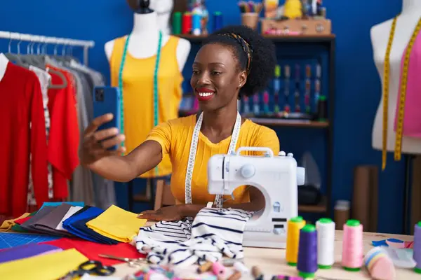 African american woman tailor make selfie by smartphone at sewing studio