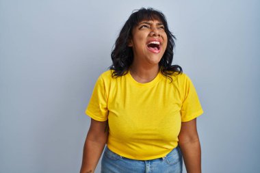 Mavi arka planda öfkeli ve kızgın bir şekilde öfkeli sinirli sinirli bağıran öfkeyle bağıran İspanyol kadın. öfke ve agresif konsept. 