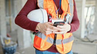 İnşaat alanında akıllı telefon kullanan genç İspanyol mimar.