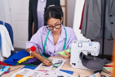 Terzide elbise tasarımı çizen genç, güzel İspanyol kadın.