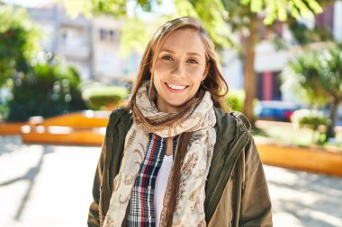 Parkta kendinden emin gülümseyen genç sarışın kadın.