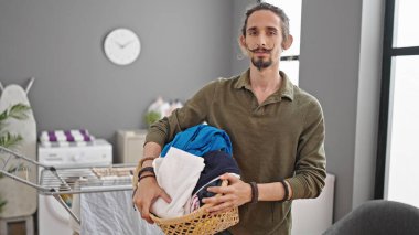 Çamaşır odasında elinde sepet tutan İspanyol genç adam.