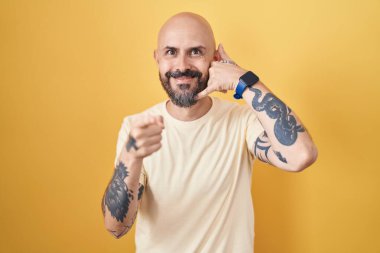 Sarı arka planda duran İspanyol dövmeli adam gülümsüyor telefonda konuşuyor ve seni işaret ediyor. Ara beni.. 