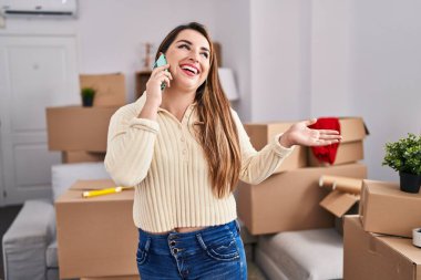 Young beautiful hispanic woman smiling confident talking on smartphone at new home