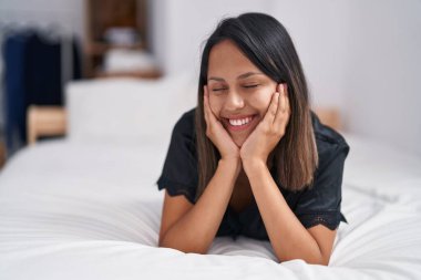 Genç İspanyol kadın yatakta kendinden emin bir şekilde gülümsüyor.